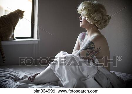 Stock Photography - Glamorous woman wrapped in sheet on bed. Fotosearch