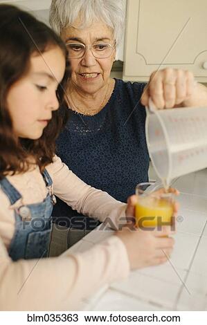 Grandmother pouring juice for granddaughter in kitchen View Large Photo Image Stock Image - Grandmother pouring juice for granddaughter in kitchen. Fotosearch