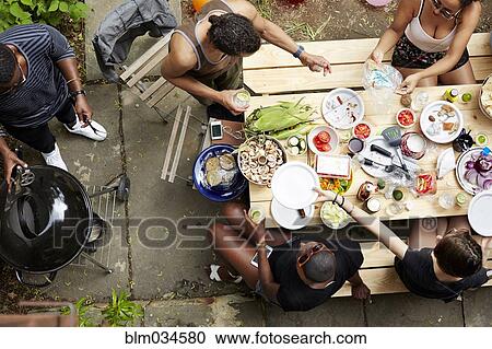 Stock Image - High angle view of friends eating at backyard barbecue. Fotosearch