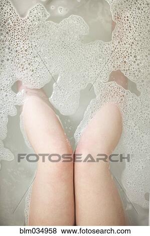 Stock Photo - High angle view of legs of woman soaking in bathtub. Fotosearch