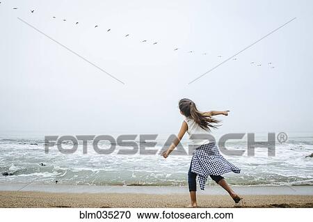 Stock Image - Hispanic girl playing on beach. Fotosearch
