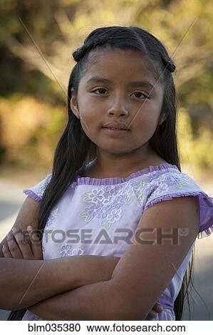 Stock Image - Hispanic girl standing with arms crossed. Fotosearch