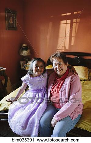 Hispanic grandmother and granddaughter sitting on bed View Large Photo Image Stock Image - Hispanic grandmother and granddaughter sitting on bed. Fotosearch