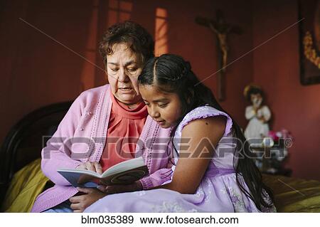 Hispanic grandmother and granddaughter reading book on bed View Large Photo Image Stock Photo - Hispanic grandmother and granddaughter reading book on bed. Fotosearch