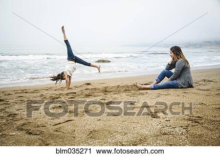 Stock Image - Hispanic mother and daughter playing on beach. Fotosearch