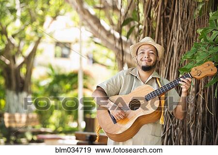 Stock Photo - Hispanic musician playing guitar in park. Fotosearch