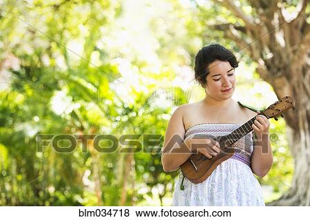 Hispanic musician playing ukulele in park View Large Photo Image Stock Photo - Hispanic musician playing ukulele in park. Fotosearch
