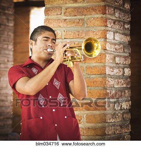 Stock Photograph - Hispanic musicians playing trumpet near brick wall. Fotosearch