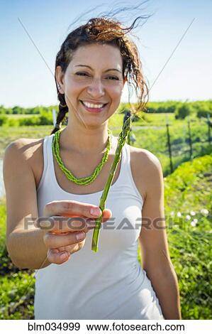 Stock Photo - Hispanic woman holding asparagus in garden. Fotosearch