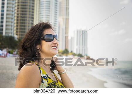 Stock Image - Hispanic woman standing on urban beach. Fotosearch