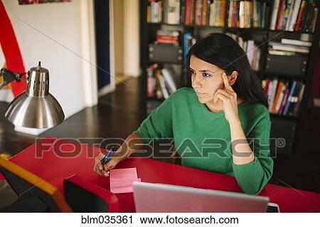Stock Image - Hispanic woman working at home office. Fotosearch