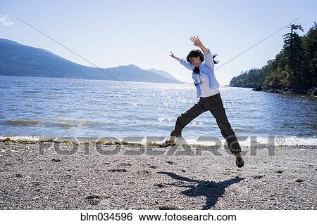 Stock Photograph - Japanese woman doing cartwheel on beach. Fotosearch
