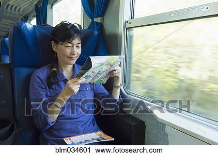 Stock Image - Japanese woman reading roadmap on train. Fotosearch
