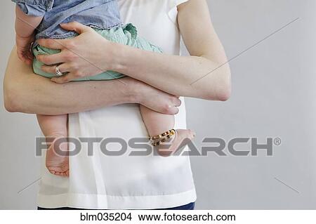Picture - Midsection view of mother holding baby. Fotosearch
