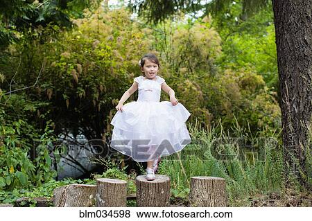 Stock Photo - Mixed race girl balancing on logs in park. Fotosearch