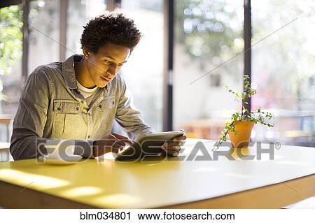 Mixed race man using digital tablet in cafe View Large Photo Image Stock Image - Mixed race man using digital tablet in cafe. Fotosearch