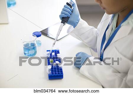Picture - Mixed race scientist pipetting sample into tube in laboratory. Fotosearch