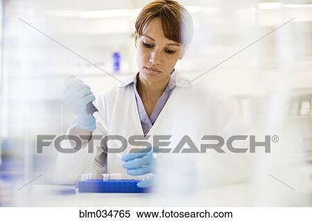 Stock Photography - Mixed race scientist pipetting sample into tube in laboratory. Fotosearch