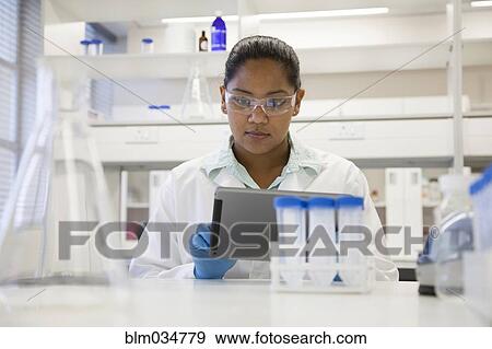 Stock Photo - Mixed race scientist using digital tablet in laboratory. Fotosearch