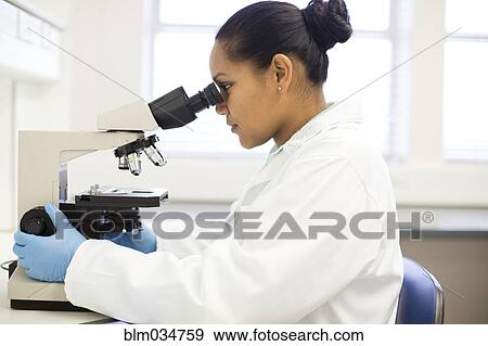 Stock Photo - Mixed race scientist using microscope in laboratory. Fotosearch