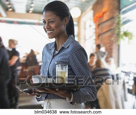 Stock Photo - Mixed race waitress serving coffee and lemonade in cafe. Fotosearch