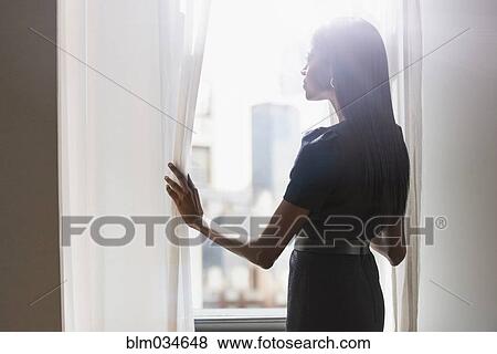 Stock Photo - Mixed race woman looking out window. Fotosearch