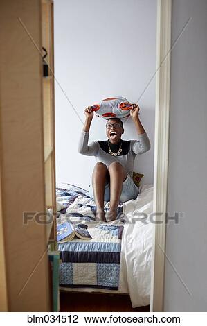 Mixed race woman playing with pillow on bed View Large Photo Image Stock Image - Mixed race woman playing with pillow on bed. Fotosearch