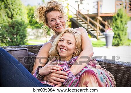 Mother and daughter hugging on backyard sofa View Large Photo Image Picture - Mother and daughter hugging on backyard sofa. Fotosearch