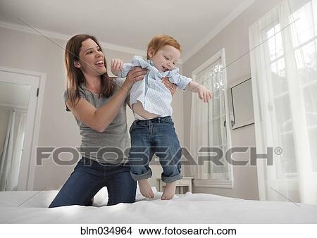 Picture - Mother and son playing on bed. Fotosearch