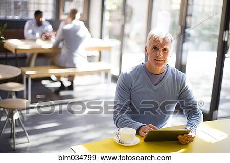 Stock Photo - Older man using digital tablet in cafe. Fotosearch