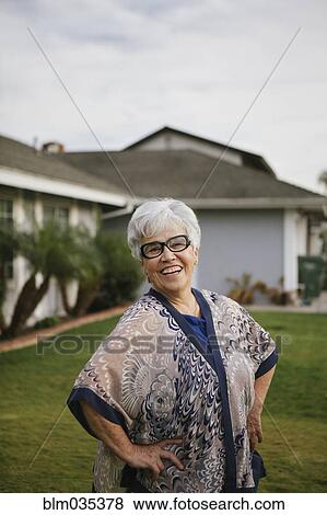 Older woman standing with hands on hips in backyard View Large Photo Image Stock Photo - Older woman standing with hands on hips in backyard. Fotosearch