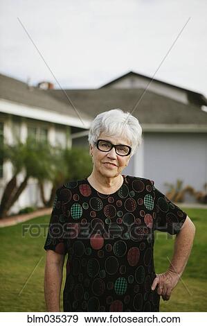Older woman standing with hands on hips in backyard View Large Photo Image Stock Photo - Older woman standing with hands on hips in backyard. Fotosearch