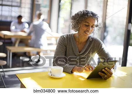 Older woman using digital tablet in cafe View Large Photo Image Stock Image - Older woman using digital tablet in cafe. Fotosearch