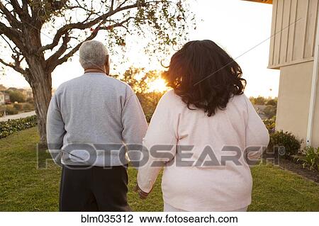 Rear view of couple walking in backyard View Large Photo Image Stock Image - Rear view of couple walking in backyard. Fotosearch
