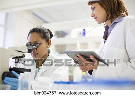 Stock Photo - Scientists using digital tablet and microscope in laboratory. Fotosearch