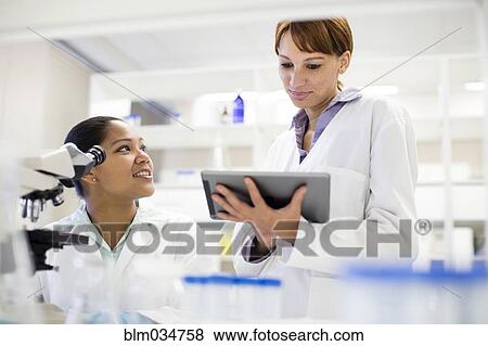 Stock Photo - Scientists using digital tablet and microscope in laboratory. Fotosearch