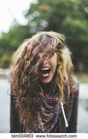 Stock Image - Shouting Middle Eastern woman tossing her hair outdoors. Fotosearch