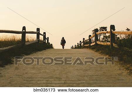Silhouette of woman walking on wooden walkway View Large Photo Image Stock Image - Silhouette of woman walking on wooden walkway. Fotosearch