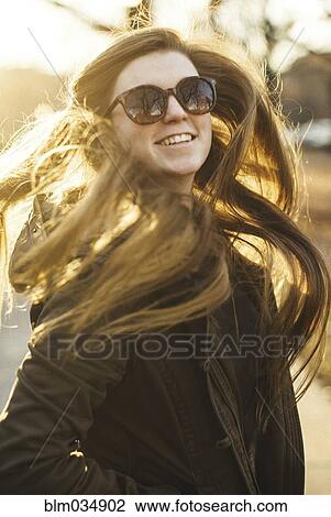 Stock Image - Smiling Caucasian woman tossing her hair outdoors. Fotosearch
