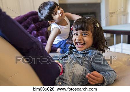 Stock Photo - Smiling girl playing on sofa in living room. Fotosearch