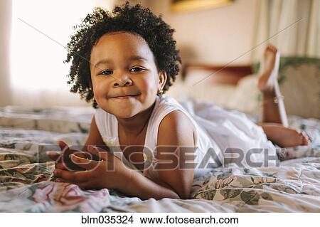 Smiling toddler girl playing on bed View Large Photo Image Picture - Smiling toddler girl playing on bed. Fotosearch