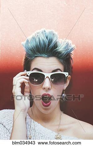 Stock Image - Surprised Caucasian woman with sunglasses and dyed hair. Fotosearch