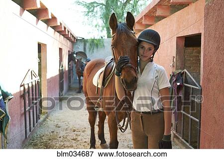 Teenage girl leading horse in stable on ranch View Large Photo Image Stock Photo - Teenage girl leading horse in stable on ranch. Fotosearch