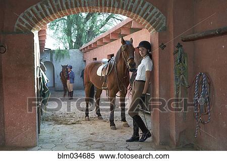 Stock Photography - Teenage girl leading horse in stable on ranch. Fotosearch