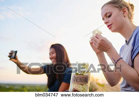 Stock Photo - Teenage girls photographing and relaxing outdoors. Fotosearch