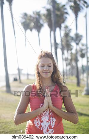 Stock Image - Woman meditating in park. Fotosearch