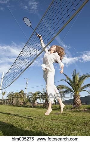 Stock Photography - Woman playing badminton in park. Fotosearch