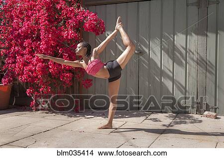 Woman practicing yoga near flowers and fence View Large Photo Image Picture - Woman practicing yoga near flowers and fence. Fotosearch