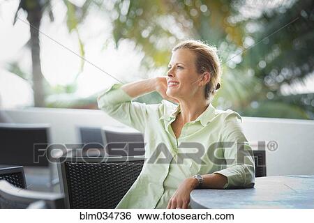 Stock Photograph - Woman sitting at patio bar. Fotosearch