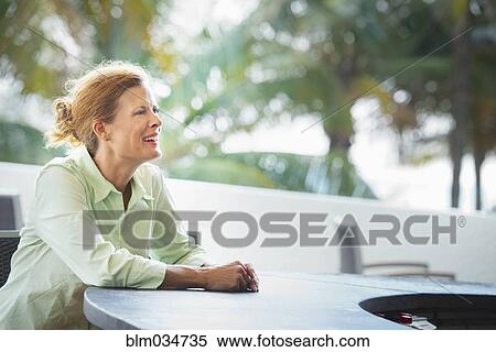 Stock Photography - Woman sitting at patio bar. Fotosearch